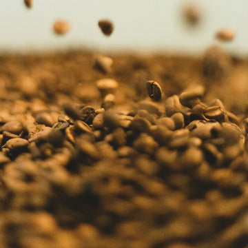 Close-up of Willow & Bloom Coffee in a stylish cup, with aromatic steam rising, on a wooden surface.